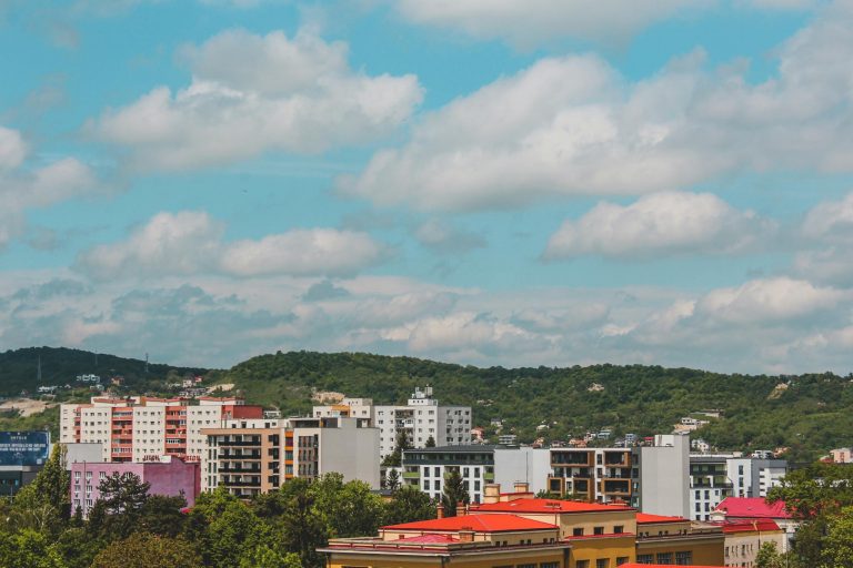 Vibrant city view featuring colorful apartment buildings with lush green hills in the background.