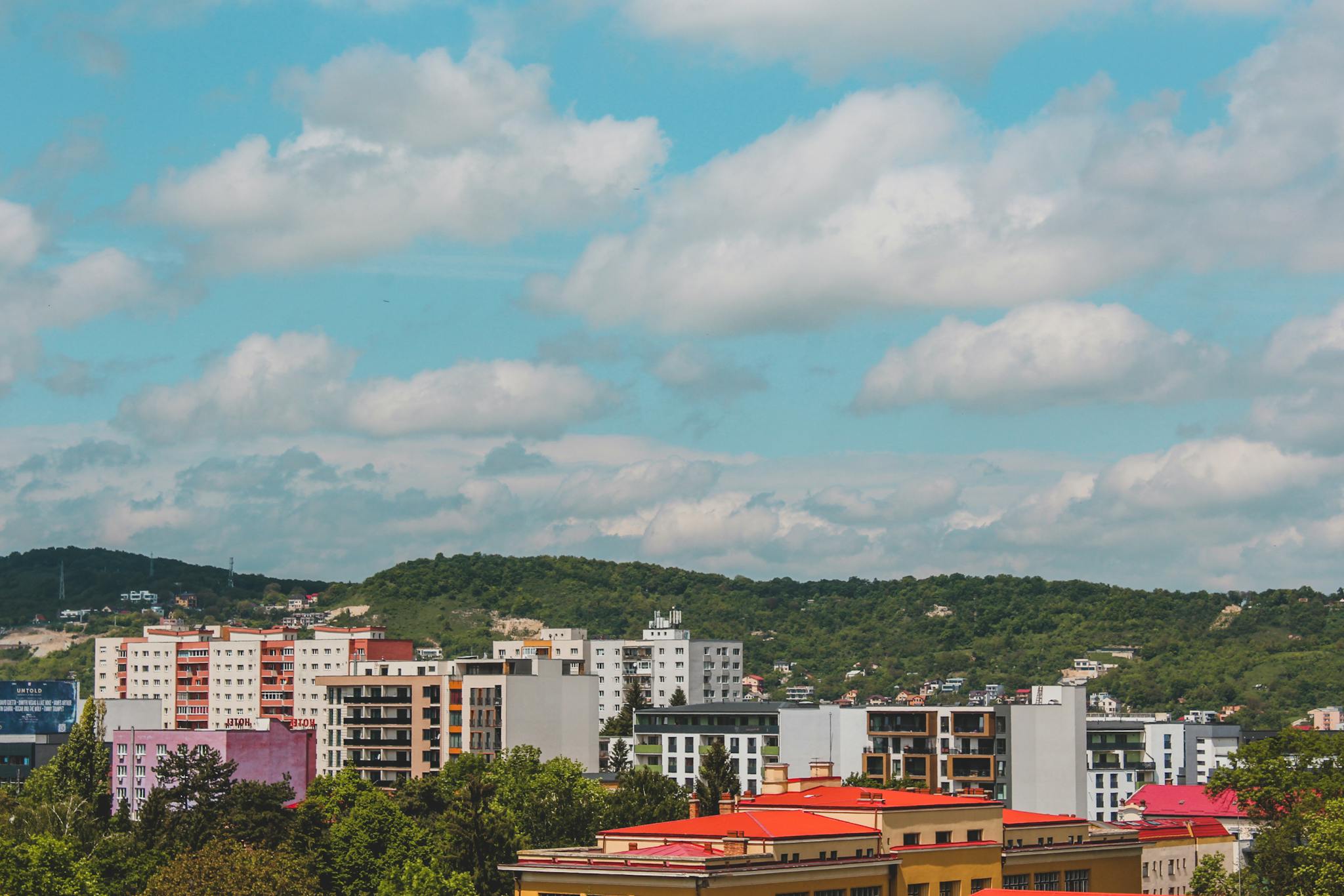Vibrant city view featuring colorful apartment buildings with lush green hills in the background.